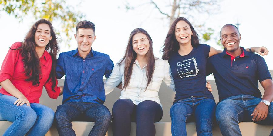 Several smiling students sitting on a bench