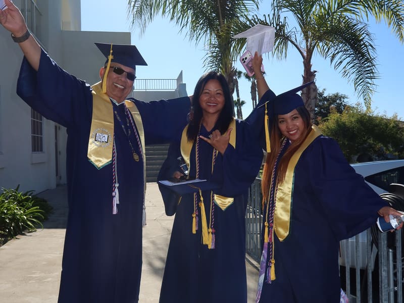 Laurus College graduates cheering with arms raised at commencement
