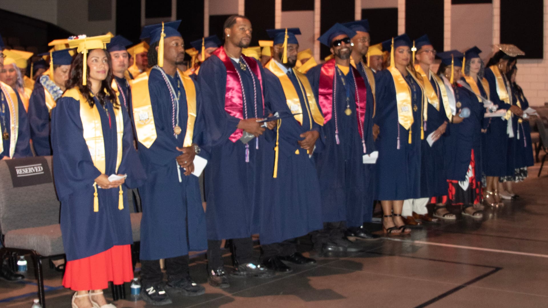 A row of Laurus College graduates in caps and gowns standing at their commencement ceremony