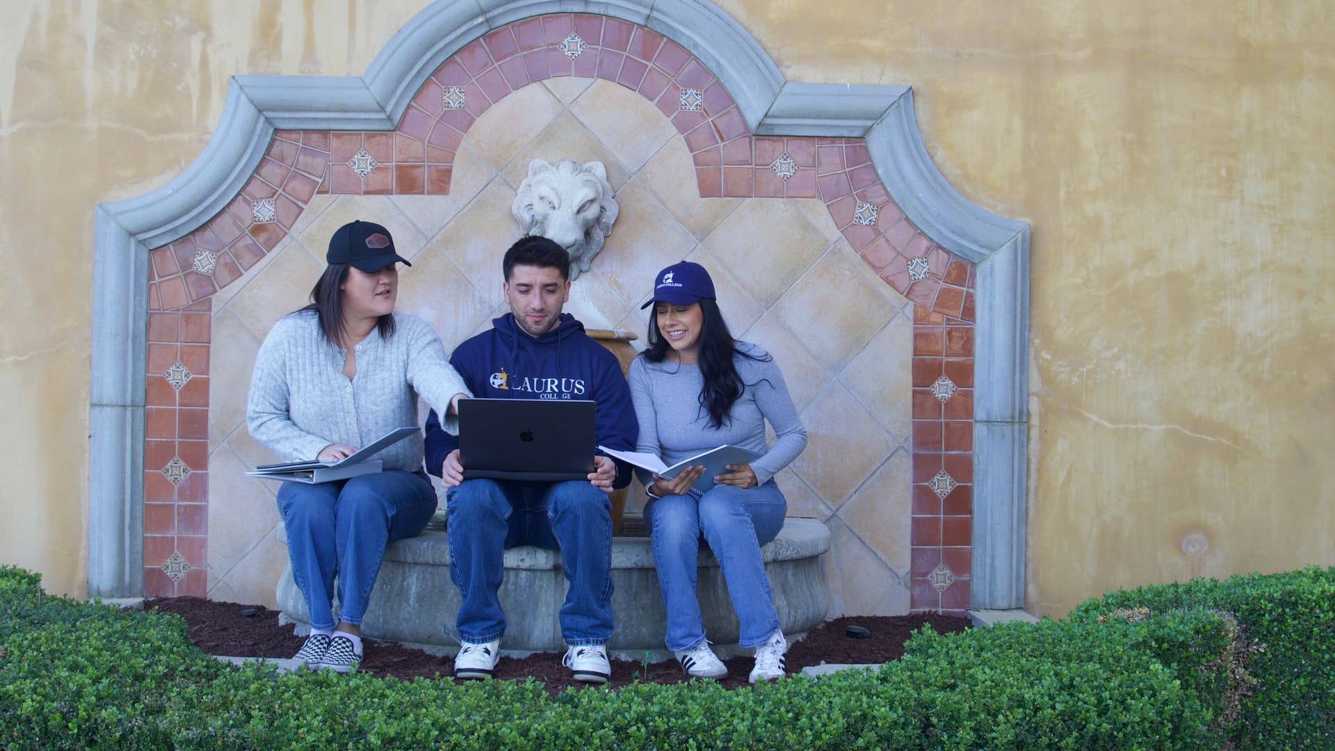 Three Laurus College students collaborating on a laptop outdoors