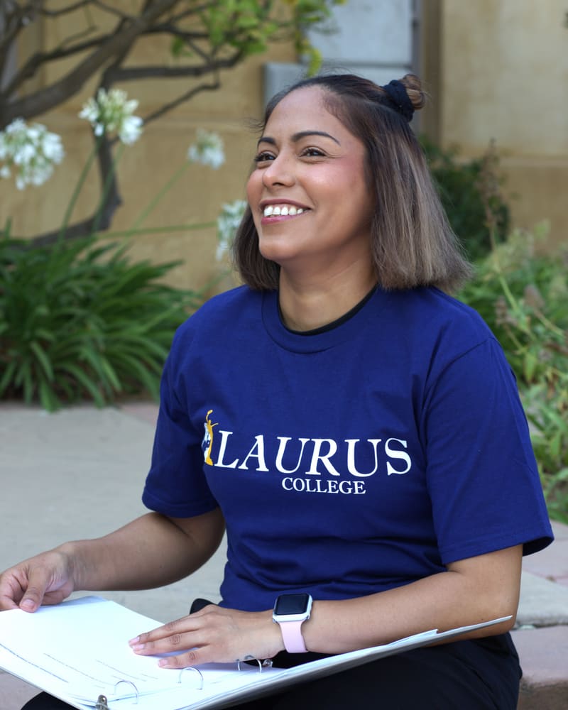 A Laurus College student in a Laurus T-shirt studying outdoors