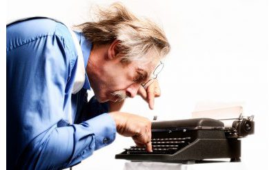 Man using two fingers to type on a typewriter