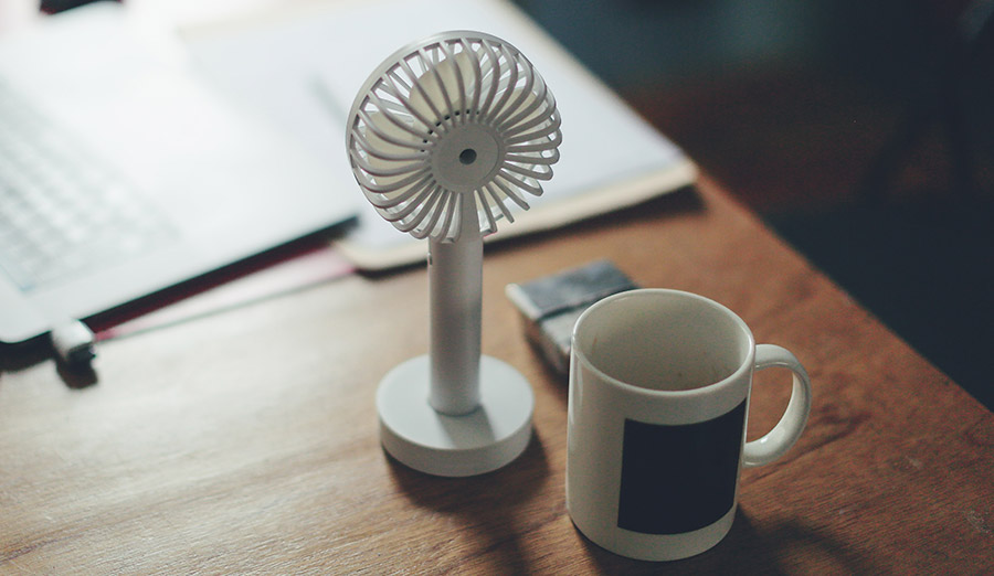 Small fan and coffee cup on desk