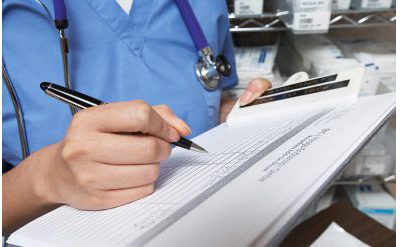 Female doctor writing in patient chart mid section