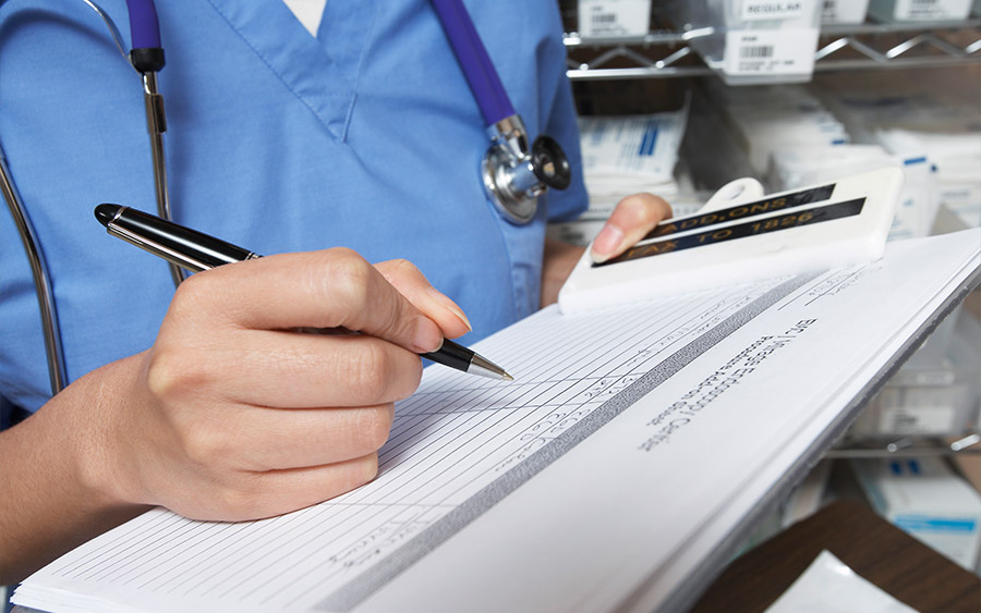 Female doctor writing in patient chart mid section