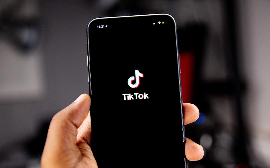 A hand holding a phone displaying the tiktok logo