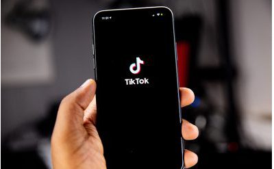 A hand holding a mobile phone with the tiktok logo